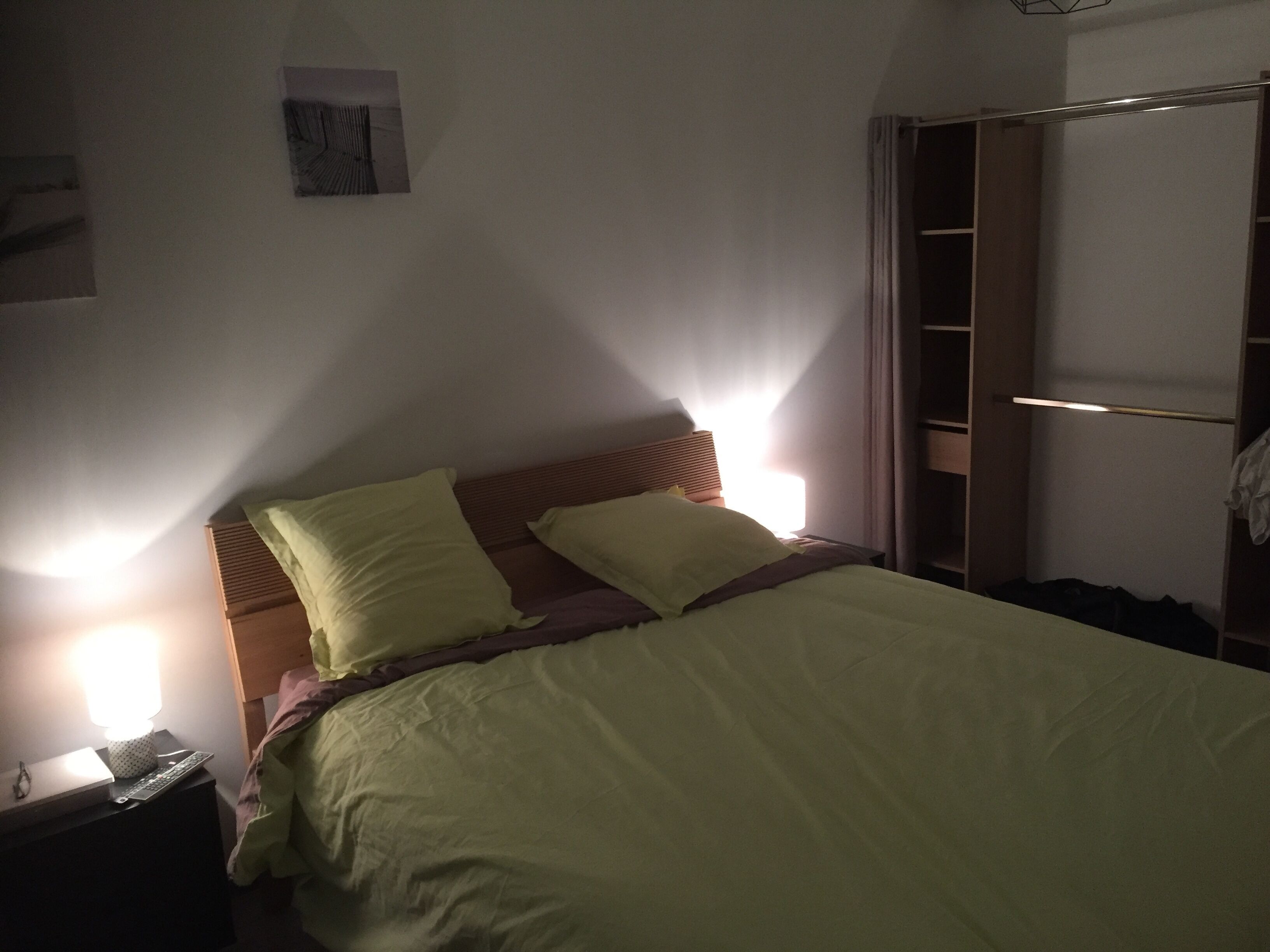 Un dormitori amb un llit, dues làmpades de nit, una tauleta de nit i un armari.