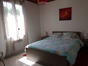 A bedroom with a bed, a nightstand, a lamp, and a window with curtains.