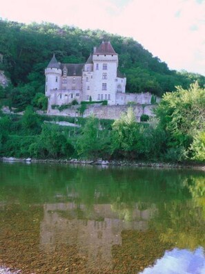 A castle-like building with multiple towers, situated on a hillside overlooking a calm river. - Charming house of the nineteenth, restored in the style of Périgord. (Cénac-et-Saint-Julien)