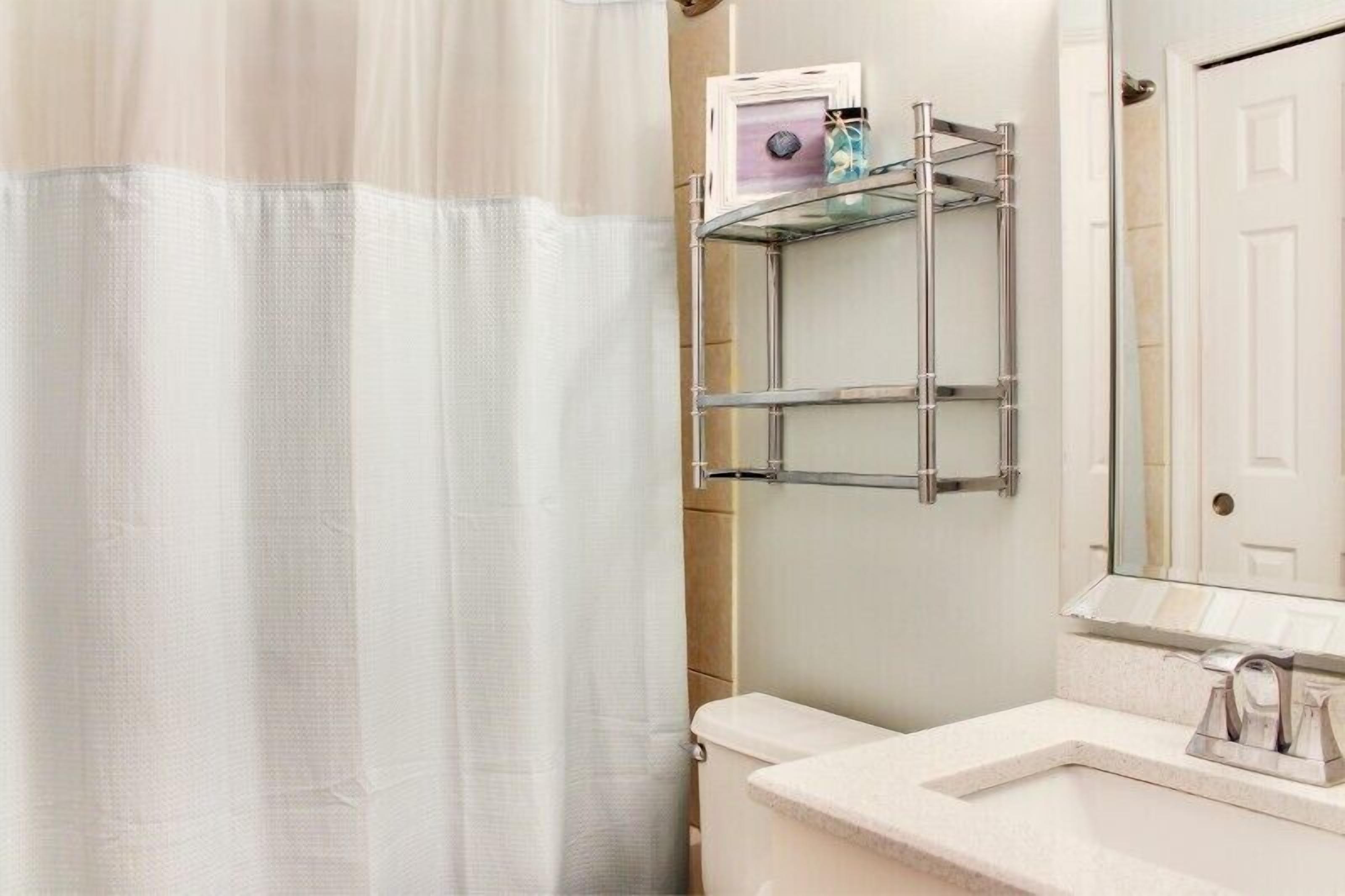 Een badkamer met toilet, wastafel, spiegel en een douchegordijn.