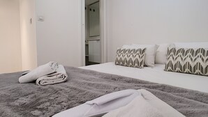 Ett hotellrum med en säng, en hopvikt handduk och ett par tofflor på golvet.