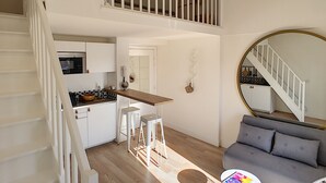En modern lägenhet i loftstil med kök, matplats och vardagsrum.