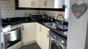 Een moderne keuken met witte kastjes, een roestvrijstalen fornuis, een magnetron en een vaatwasser.