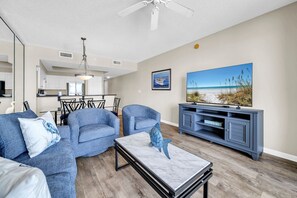 A living room with a sofa, chairs, a coffee table, a TV stand, and a painting on the wall.