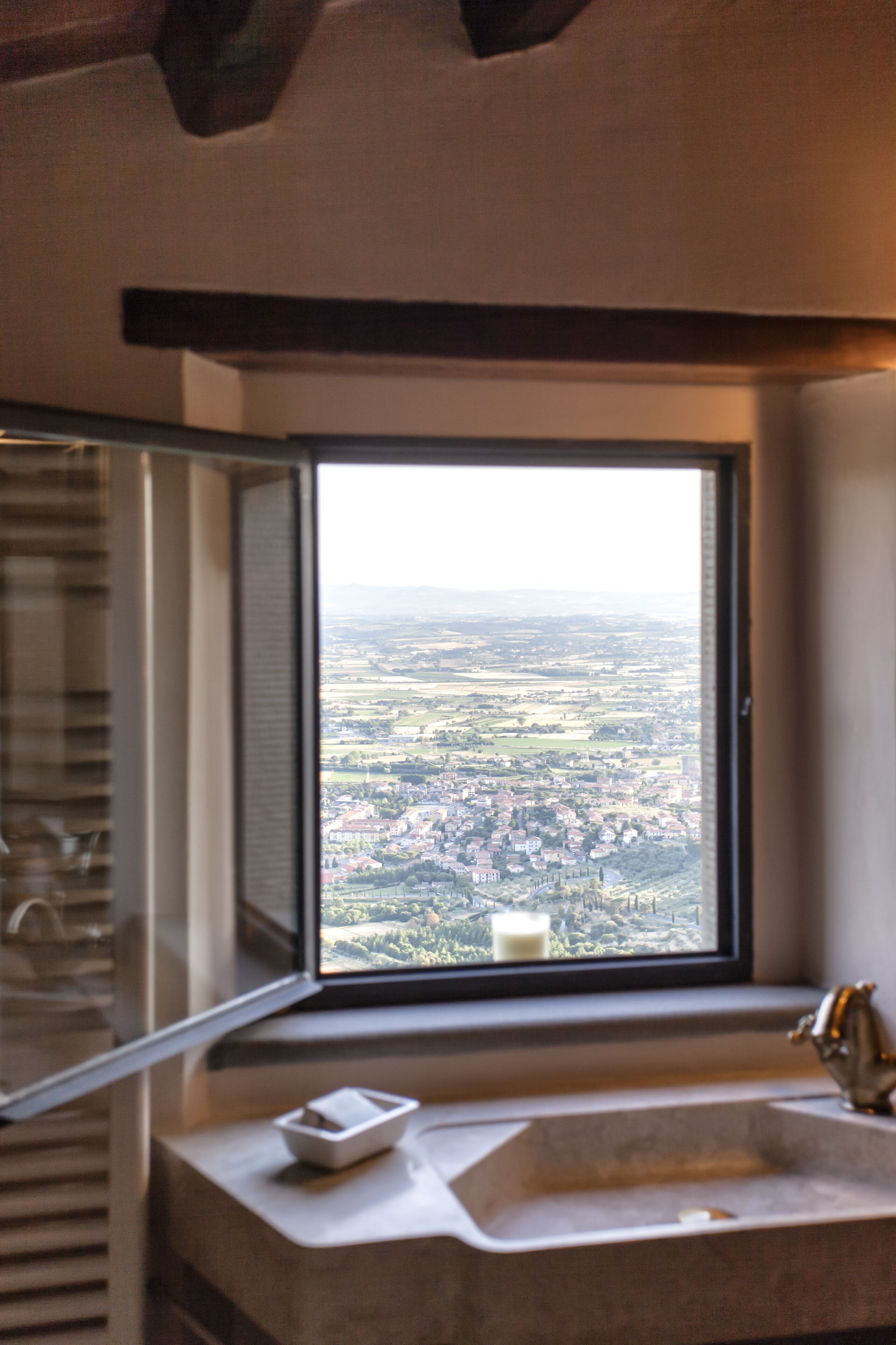 Ein Badezimmer mit einem großen Fenster und Blick auf eine Stadtlandschaft.