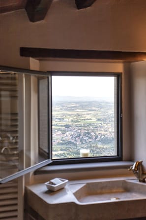 Ein Badezimmer mit einem großen Fenster und Blick auf eine Stadtlandschaft.