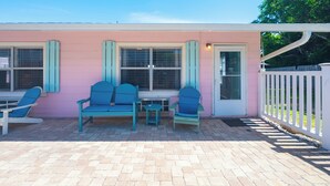 Un edificio rosa con un patio que tiene sillas azules y una mesa.