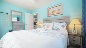 Un dormitorio con cama, lámparas de noche, cómoda, espejo y puerta que da a un armario.