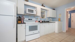 Una cocina con armarios blancos, un microondas, una estufa y un lavamanos.