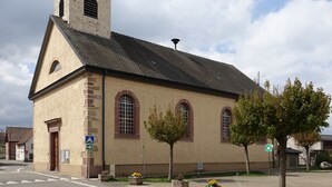 Una iglesia con una torre del reloj, ventanas de arco y una campana.