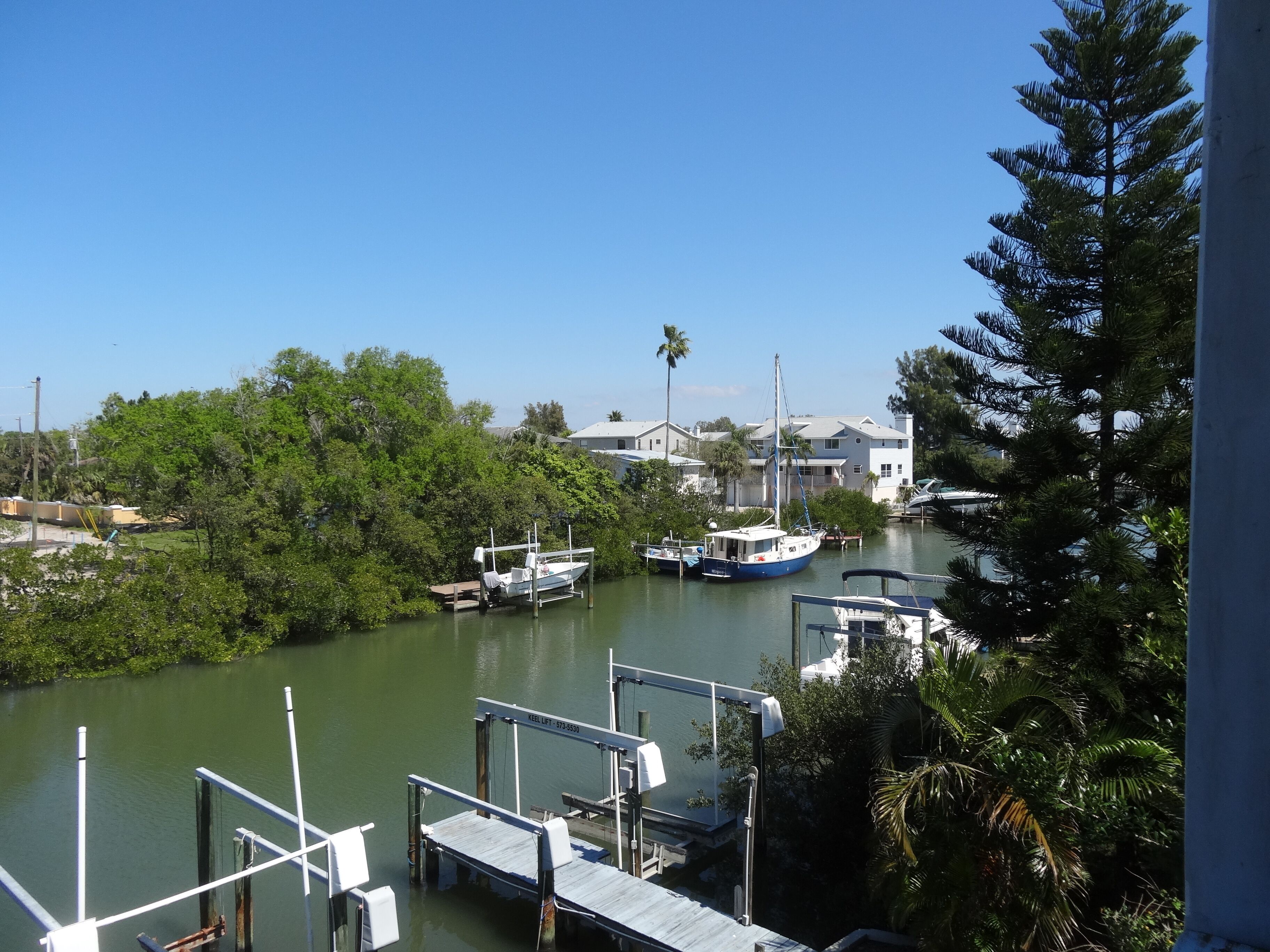 Marina con barcos amarrados, rodeada de vegetación y edificios residenciales.