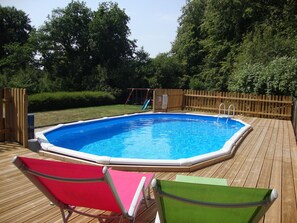 A rectangular swimming pool with a wooden deck, surrounded by a wooden fence, and two lounge chairs. - Idyllic Rural Retreat. Pool & Games Room. IDEAL COUPLES, FAMILY OR INDEPENDENTS (Lanrivain)