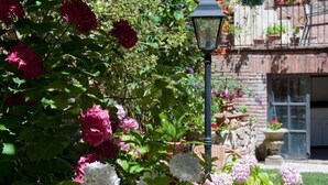 Een tuin met verschillende bloemen en een stenen muur met plantenpotten.