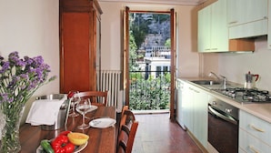 Een keuken met een eettafel gedekt voor twee personen, uitzicht op een balkon en een fornuis.