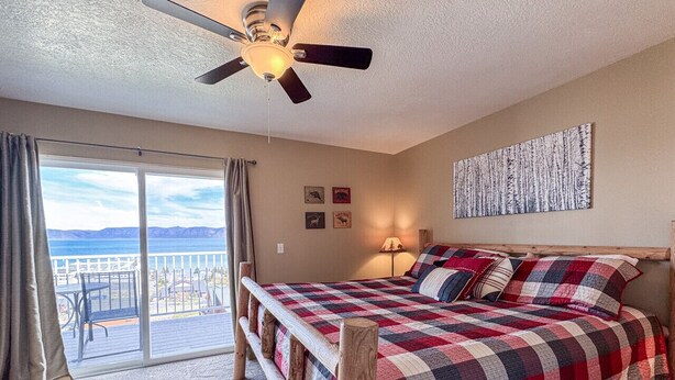 Ein Schlafzimmer mit einem großen Bett, einem Deckenventilator, Blick auf den Ozean und einem Balkon.