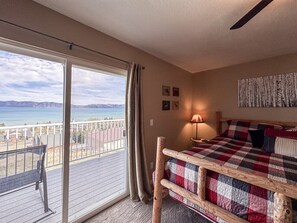 Une chambre avec un lit, un balcon, une vue sur la mer et une tête de lit en bois.