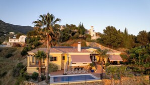 Une villa de style méditerranéen dotée d’un mur de soutènement en pierre, d’une piscine et offrant une vue sur les collines environnantes.