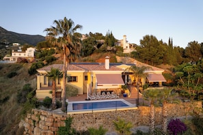 A Mediterranean-style villa with a stone retaining wall, a swimming pool, and a view of the surrounding hills. - Ultra-Luxury Family Home: Breathtaking Views, Retro Cinema & Americana diner. (Mijas)