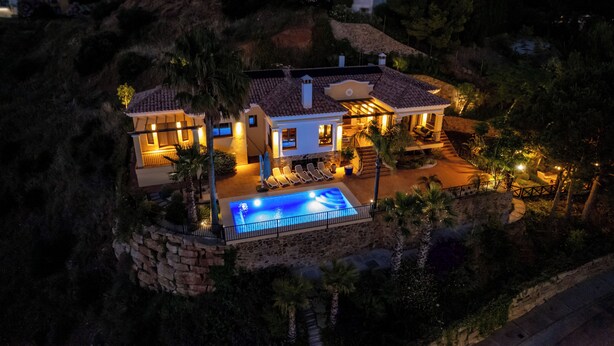 Une villa située sur une colline, dotée d’une piscine, d’un espace salon extérieur et d’une terrasse bien éclairée.