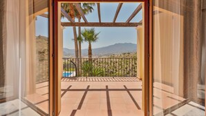 Un balcon avec vue sur les montagnes, une piscine et des palmiers.