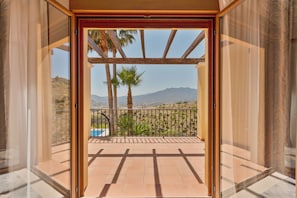 A balcony with a view of mountains, a pool, and palm trees. - Ultra-Luxury Family Home: Breathtaking Views, Retro Cinema & Americana diner. (Mijas)