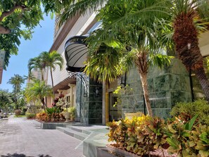A hotel entrance with a sign reading "HOTEL GARDEN," surrounded by lush greenery and a paved walkway. - Ocean Views, Waikiki Resort! Extra Large 1-Bedroom Suite, Full Kitchen & Laundry (Honolulu)