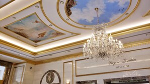 Un intérieur luxueux agrémenté d’un lustre, d’un plafond orné et d’une enseigne indiquant : « Royal Garden at WAKKI ».