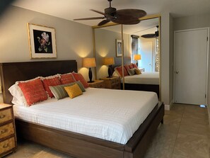 Ein Schlafzimmer mit einem großen Bett, einem Deckenventilator, einem Spiegel und einer Tür.