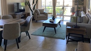 A spacious living room with a dining area, a sofa, a coffee table, and a TV. - Affordable Paradise  (Kihei)