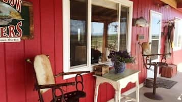 Step into a charming fishing retreat with a welcoming porch, complete with a large window, a small table, and a metal chair.