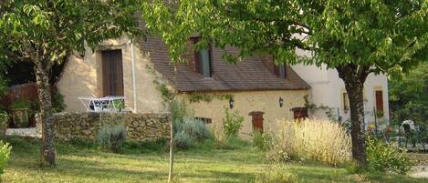 Una casa rústica con pared de piedra, puerta de madera y una ventana.