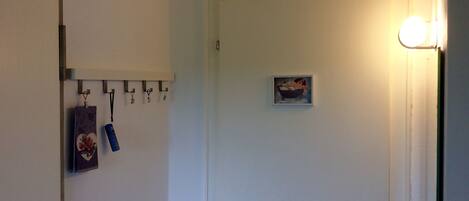 A room with a white door, a small framed picture on the wall, and a light fixture above the door.
