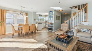 A spacious living area with a dining table, chairs, a sofa, and a staircase.