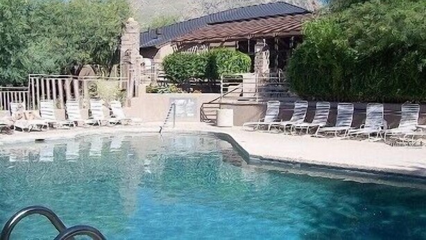 A swimming pool with lounge chairs and a building with a sloped roof in the background. - Rare Ventana Canyon Intimacy,  Heated Pools, Tennis (Tucson)