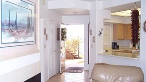 A living room with a beige leather sofa, a fireplace, and a kitchen area visible through an open door. - Rare Ventana Canyon Intimacy,  Heated Pools, Tennis (Tucson)