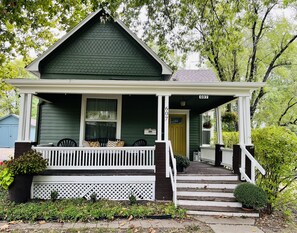 A green house with a white porch, a front door, and a number 607 sign. - Relaxing 3 bedroom home w/ full kitchen & WiFi; walking distance to restauraunts (Lee's Summit)