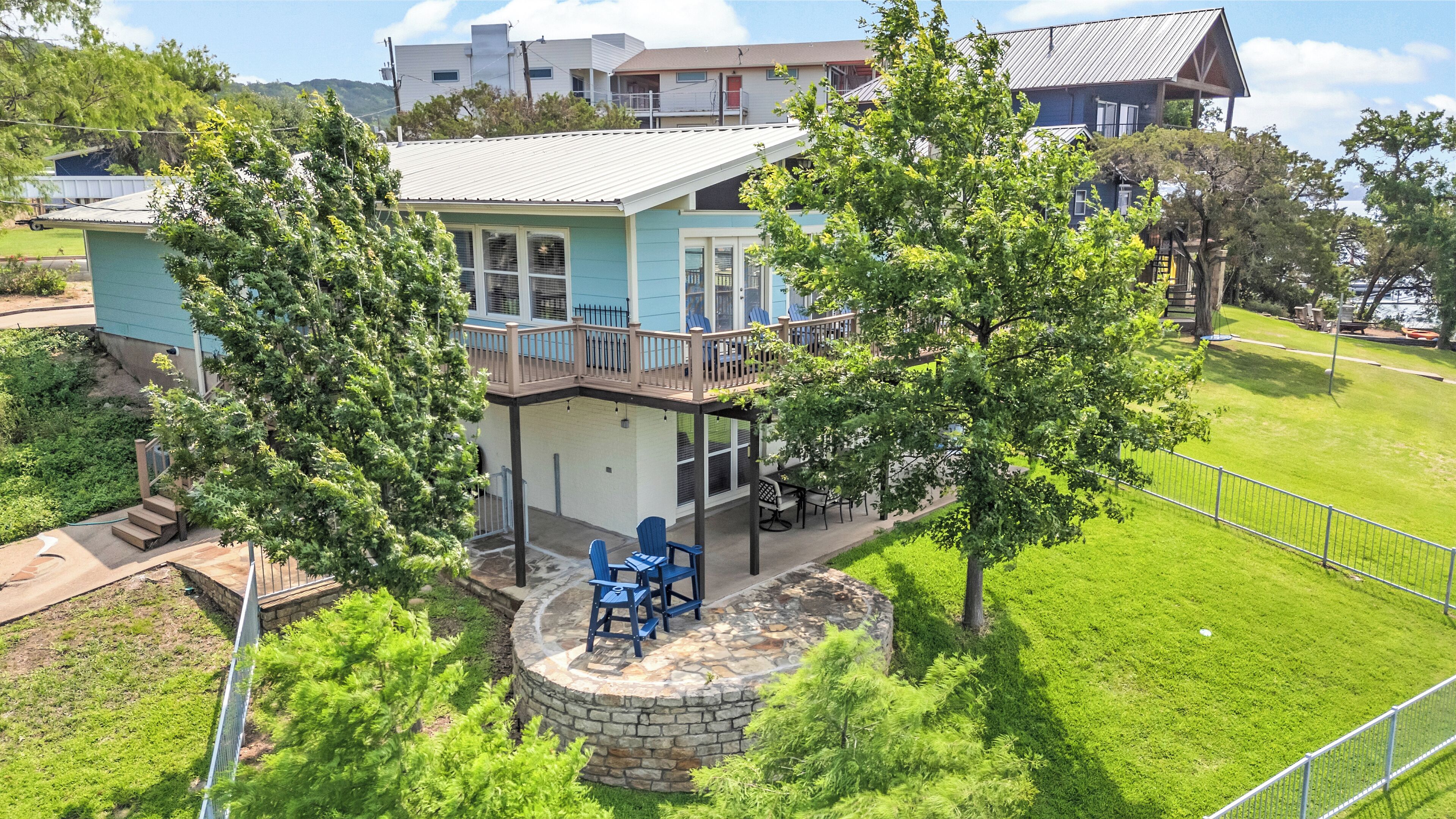 A two-story house with a balcony, a stone patio, and a fenced yard.