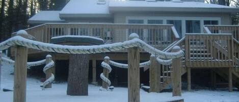A wooden deck with a name sign reading "Lorenzo," surrounded by snow and trees.