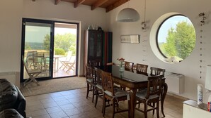 A dining area with a wooden table and chairs, a cabinet, a large window, and a ceiling with exposed beams. - Idyllic Villa, with Infinity Pool, 4 air conditioned bedrooms  & stunning views. (Torino di Sangro)
