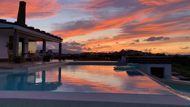 A modern pool with a sunset view, a covered patio with seating, and a brick chimney. - Idyllic Villa, with Infinity Pool, 4 air conditioned bedrooms  & stunning views. (Torino di Sangro)