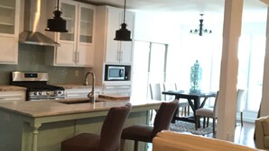 A modern kitchen with white cabinets, a central island, and pendant lighting.