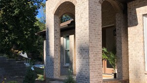 A brick house with a covered porch and a small garden.