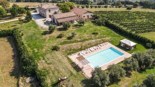 Eine großzügige Villa mit Schwimmbad, umgeben von Weinbergen und einer hügeligen Landschaft.