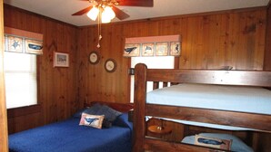 A cabin-style room with wooden walls, a bunk bed, a ceiling fan, and framed pictures on the wall. - CAPTAINS QUARTERS - AN ALL INCLUSIVE VACATION RENTAL LOCATED IN SOUTHERN SHORES! (Kitty Hawk)
