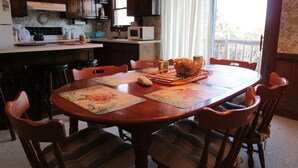 A dining area with a wooden table, chairs, and a basket of bread. - CAPTAINS QUARTERS - AN ALL INCLUSIVE VACATION RENTAL LOCATED IN SOUTHERN SHORES! (Kitty Hawk)
