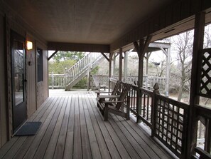 A wooden deck with a staircase leading to a higher level, a bench, and a door. - CAPTAINS QUARTERS - AN ALL INCLUSIVE VACATION RENTAL LOCATED IN SOUTHERN SHORES! (Kitty Hawk)