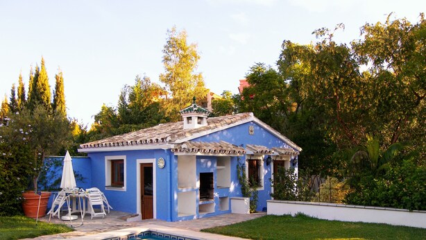 Une maison bleue avec un toit en tuiles, une piscine et une pelouse.