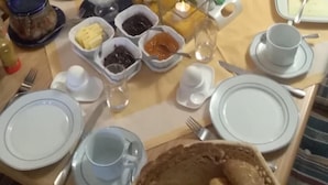 Une table à manger dressée avec différents plats, notamment des fruits, des condiments et du pain.