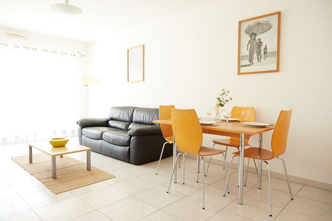Ein modernes Wohnzimmer mit einem grauen Sofa, einem Holzespeisetisch mit vier Stühlen und einem kleinen Couchtisch.