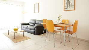 A modern living room with a grey sofa, a wooden dining table with four chairs, and a small coffee table.